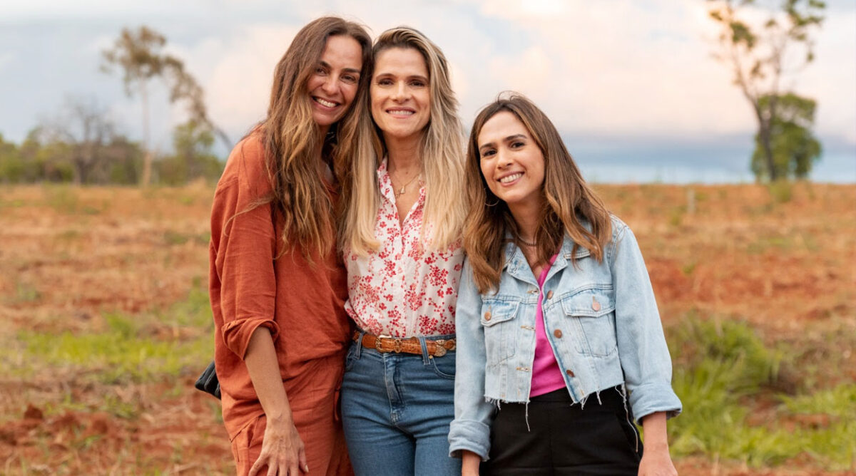 Três mulheres abraçadas em um campo. Imagem de Minha Irmã E Eu, nova comédia protagonizada por Ingrid Guimarães e Tatá Werneck.